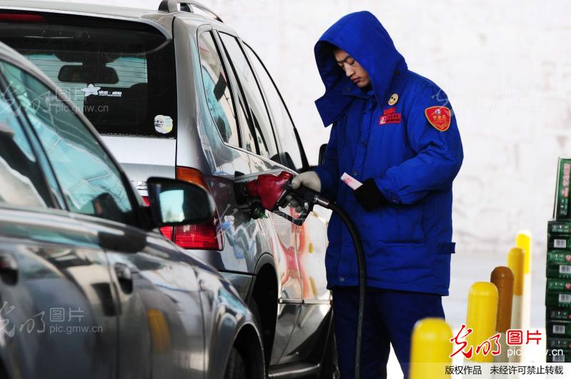 山东青岛一加油站工作人员在为汽车加油。